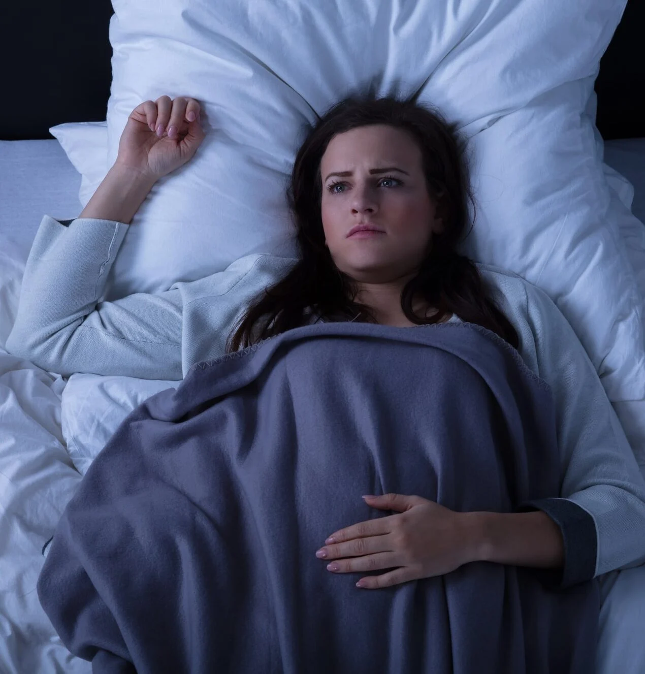Elevated View Of A Sad Young Woman Lying On Bed-min Elevated View Of A Sad Young Woman Lying On Bed